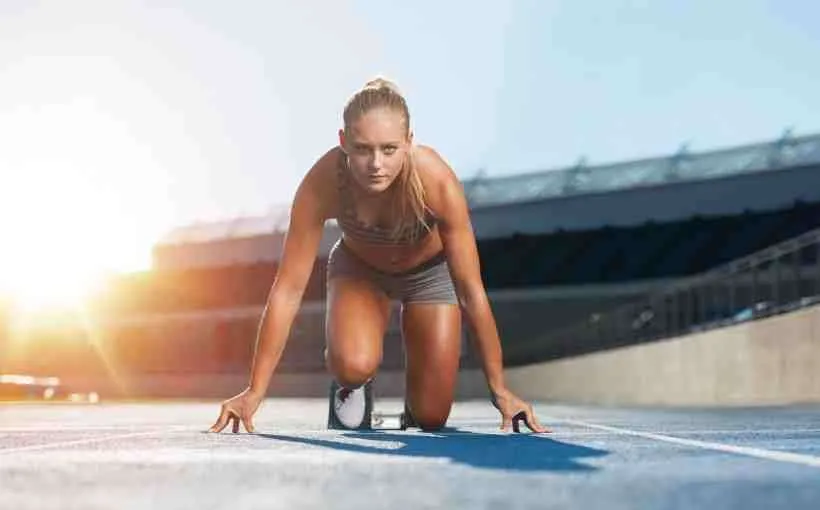 Sprinter crouched in the starting blocks on a track at sunrise, ready to launch, like a business getting in early on new platforms