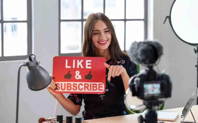 Influencer filming a video and pointing to a "Like & Subscribe" sign, showing how creators drive trends
