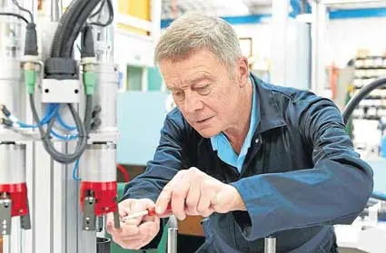 Older worker in a navy jacket focused on adjusting machinery, representing the "Endurers" in quadrant 3
